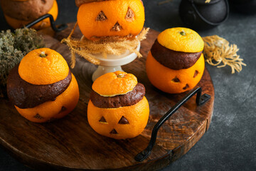 Halloween party jack-o-lantern chocolate orange cakes against the background of the old forest, branches and leaves. Halloween food concept. Sweets for Halloween celebration.