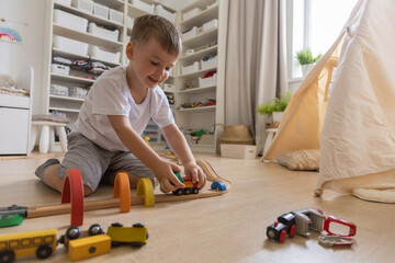 Preschool baby boy playing wooden Montessori materials rainbow arch railways at childish room
