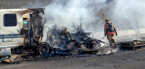 RV fire aftermath on interstate highway.