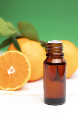 Natural organic orange essential oil for skin face and body health care. Moisturizing, aromatherapy, detox treatment, anti-stress effect. Fresh fruit, green leaves, green background