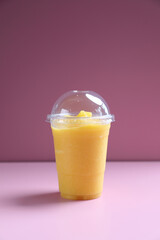 Mango smoothie milk shake with take out glass isolated on pink background