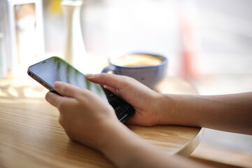 Woman hand using a smartphone for Stock exchange trading online in the coffee shop, business concept