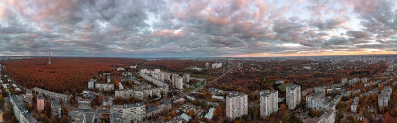 Aerial wide sunset panorama view on autumn city with telecommunication tower in forest near...