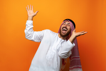 Successful smiling young Arab man celebrating victory on orange background