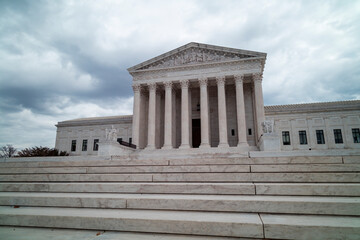 The United States Supreme Court Building in Washington, DC, is seen from the west entrance on a grey and cloudy winter day. No people are seen. Low angle wide shot.
