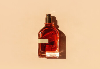 Transparent perfume bottle with red filling on a pastel beige background in the sunlight. Flat lay, top view. Luxury presentation mockup. Beautiful opened glass of aroma water