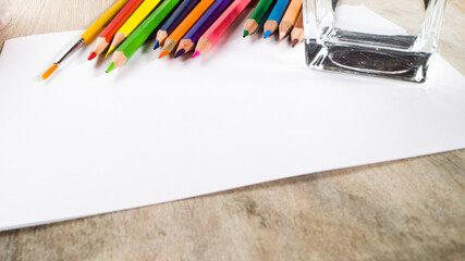 Colorful watercolor pencils and brushes on a white background.