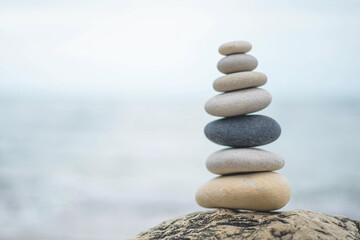 Fototapeta na wymiar Pebble tower balance harmony stones arrangement on sea beach coastline peaceful formation pyramid