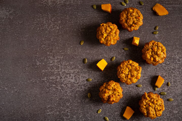 Pumpkin and oatmeal muffins on a gray table with pieces of pumpkin. Healthy dietary dessert. Healthy eating