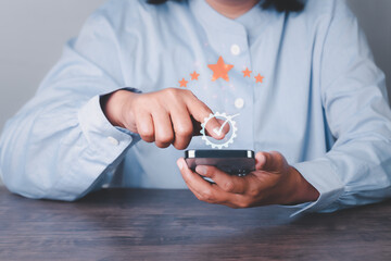 Fototapeta premium close up woman hand using smartphone with popup five star icon for feedback review satisfaction service, Customer service experience and business satisfaction survey. ideas design customer reviews.