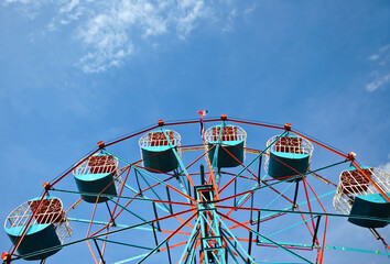A multicolored ferris wheel against a blue sky background 