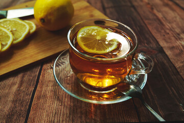 transparent mug with black tea and yellow lemon on the table.