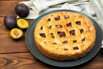 shortcake with plums on a wooden table. the concept of homemade shortcrust pastry. baked fruit dessert on the kitchen table close up