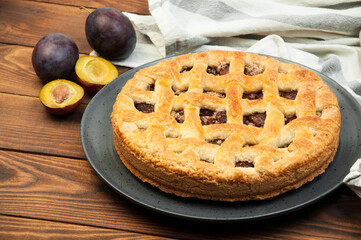 shortcake with plums on a wooden table. the concept of homemade shortcrust pastry. baked fruit dessert on the kitchen table close up
