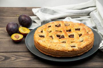shortcake with plums on a wooden table. the concept of homemade shortcrust pastry. baked fruit dessert on the kitchen table close up