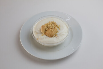 Magnolia dessert decorated with biscuits in a glass bowl on a white plate isolated on white