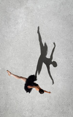 Portrait of young ballerina in black dress performing isolated over grey wall background. Top view. Shadow element. Twine
