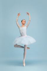 Fototapeta na wymiar Portrait of tender, beautiful, young ballerina dancing, performing isolated over blue studio background. Femininity