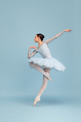 Portrait of tender young ballerina dancing, performing isolated over blue studio background. Tenderness, grace and elegance - obrazy, fototapety, plakaty