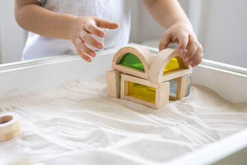 Cute male kid playing with sensory box kinetic sand table Montessori material wooden ecology toys