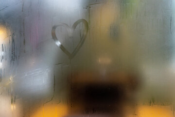 A heart painted on a misted window. Heart on misted glass. Heart on a window background. Heart symbol of love drawn on the glass.