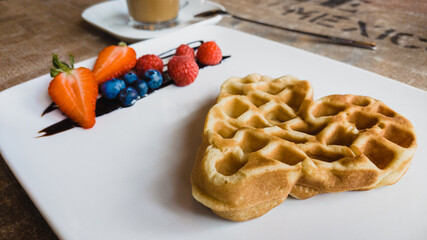 Waffel with healthy fruits arranged on a white plate