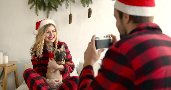 Man photographing wife with French bulldog