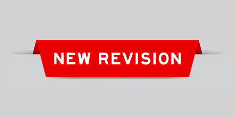 Red color inserted label with word new revision on gray background