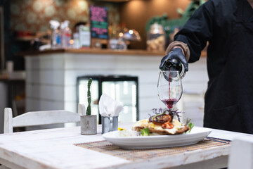 prepearing the table with a man serving red wine on a glass