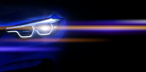 Car headlights with light rays and copy space, banner. Neon yellow and blue light of car headlights on a dark background, panorama, close up .