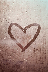 Drawing on the window: Heart. Autumn rainy weather. Finger drawing on the misted glass