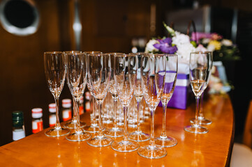 A lot, a row of empty transparent wine glasses stands on a wooden table in a bar, cafe close-up.