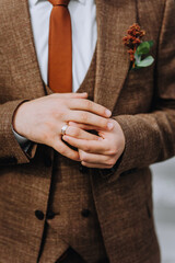 The groom puts a gold ring on his finger at the ceremony, worrying. Close-up wedding photography, portrait.