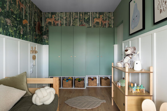 Stylish composition of cozy scandinavian child's room interior with wooden bed, plush and wooden toys, furniture and beautiful wallpaper. Creative wall, carpet on the floor. Template.	