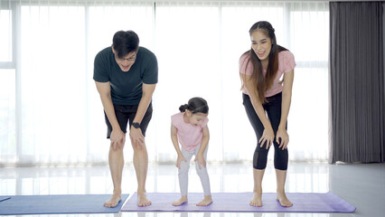 cheerful happy Asian family with father mother and daughter making a home exercise together.