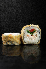 Fried sushi rolls with rice, chicken and herbs on a black background with reflection