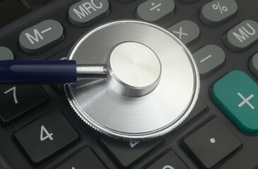 Stethoscope on black calculator close up. Cost of medicine and medical insurance concept.