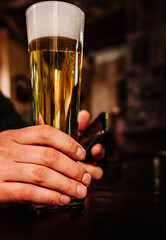 man holds a glass of beer in his hand at the bar or pub