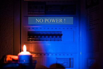 hand with candle in darkness room on electricity switch box. Power outage, blackout, no power...