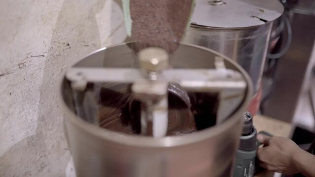 Crop chocolatier adding cacao powder into machine
