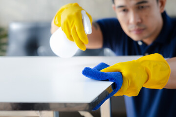 Person cleaning the room, cleaning staff is using cloth and spraying disinfectant to wipe the...