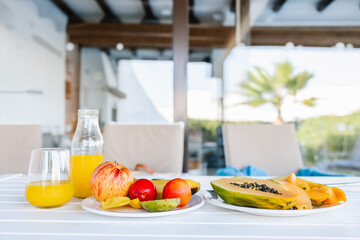 Plates of assorted exotic fruits and juice bottle served on table on terrace