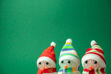 three Christmas snowmen glow on a green background with a place for text , a creative Christmas concept