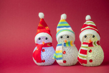 three Christmas snowmen glow on a red background with a place for text , a creative Christmas concept