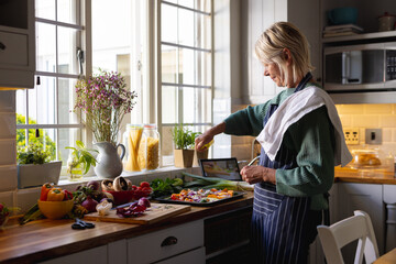 Happy senior caucasian woman standing in kitchen and preparing dinner