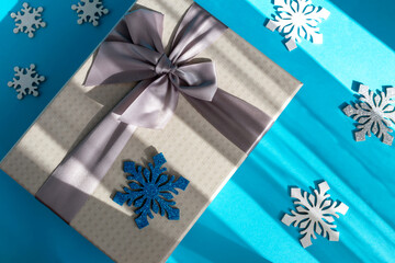 Gray gift box with bow and different snowflakes on blue background