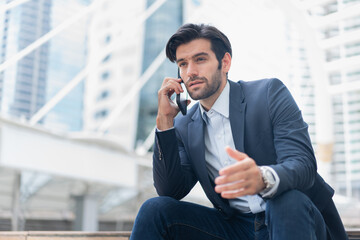 Urban business man talking on smart phone traveling walking at park . Casual young businessman wearing suit jacket . Handsome male model .