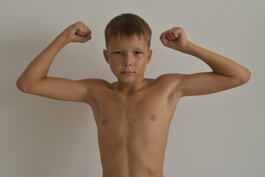 Athlete boy demonstrates muscle strength by raising his arms up.