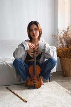 Young beautiful lady squart down nd put violin,in front of her body,looking with romantic emotion,