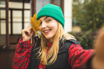 The girl holds a maple leaf in her hands and enjoys autumn. Autumn photo. The girl is holding an autumn leaf in her hands and smiling.